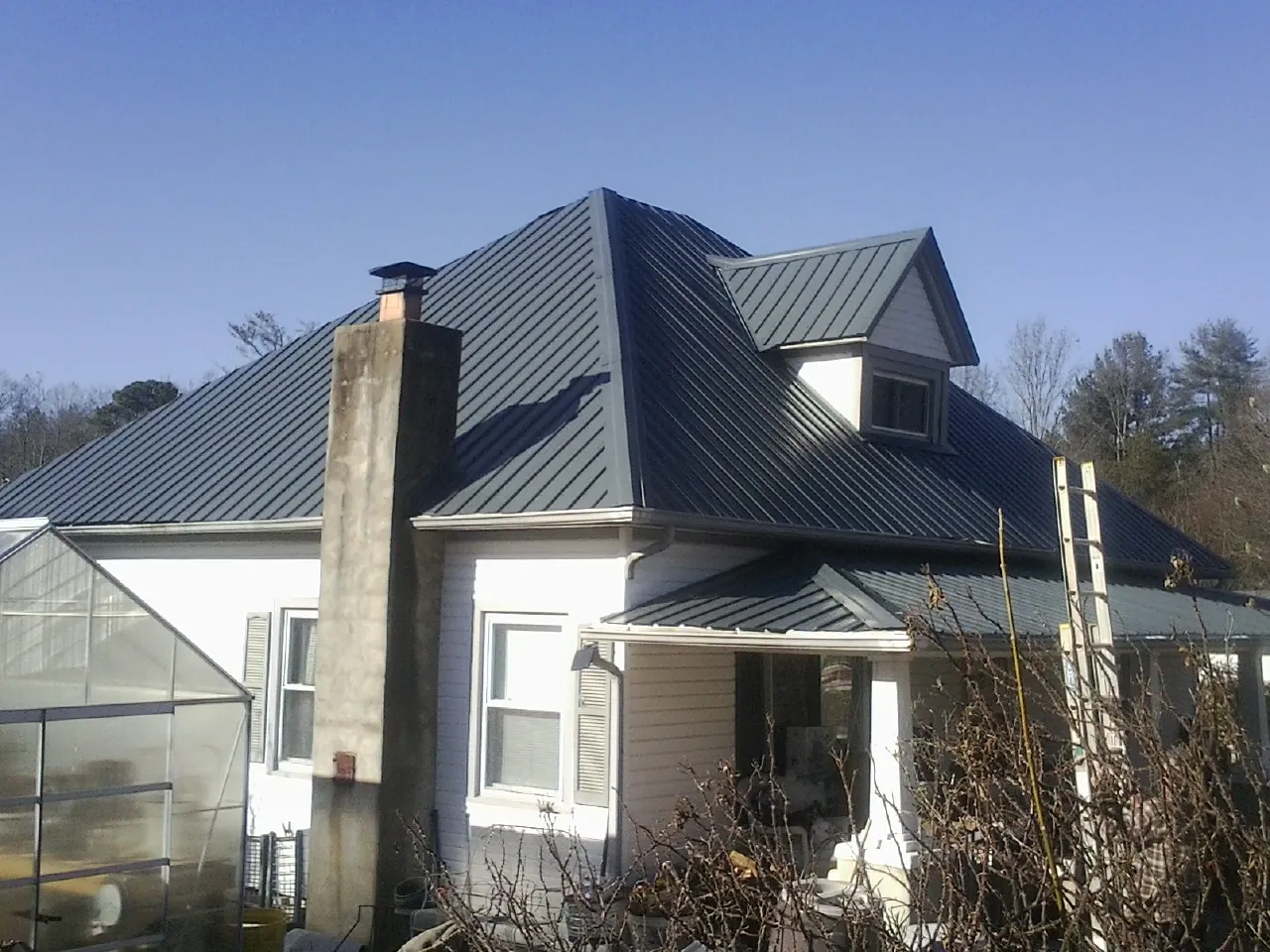 Dark blue standing seam metal roof on a white farmhouse with dormer — Slate & Tile Roof Repair by Roofing Brothers in West Wareham