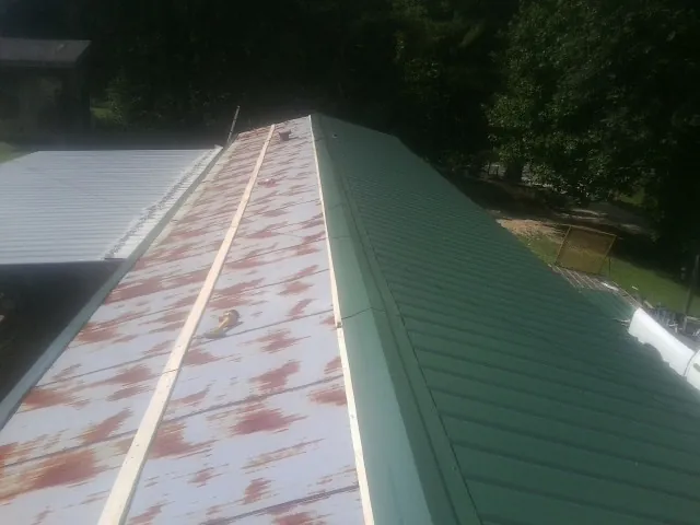 Old rusted panels beside newly installed green metal roofing — Wind Damage Roof Repair by Roofing Brothers in West Wareham
