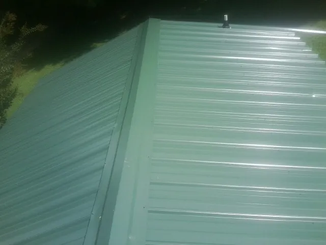 New green metal panels meeting at the ridge of a roof — Flat Roof Repair work by our crew in West Wareham