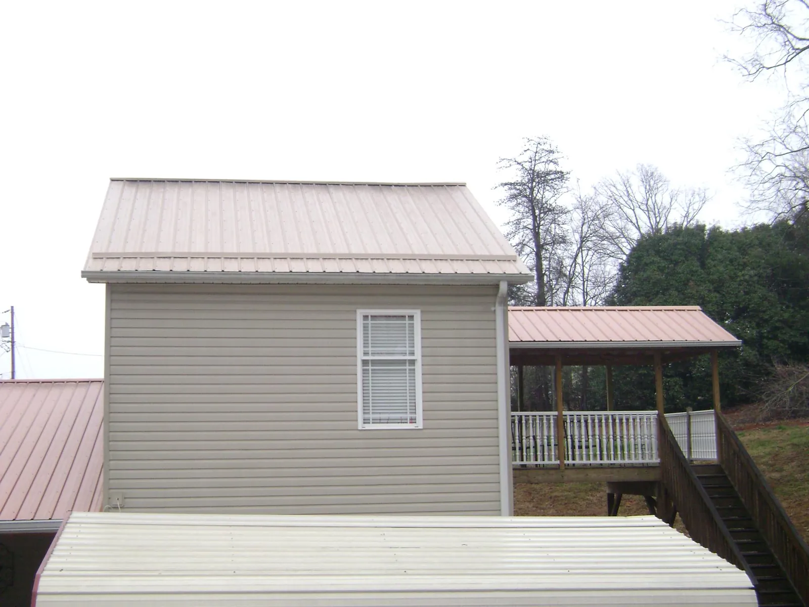 Tan metal roofs on a two story addition and attached porch, from a Roof Replacement job in West Wareham