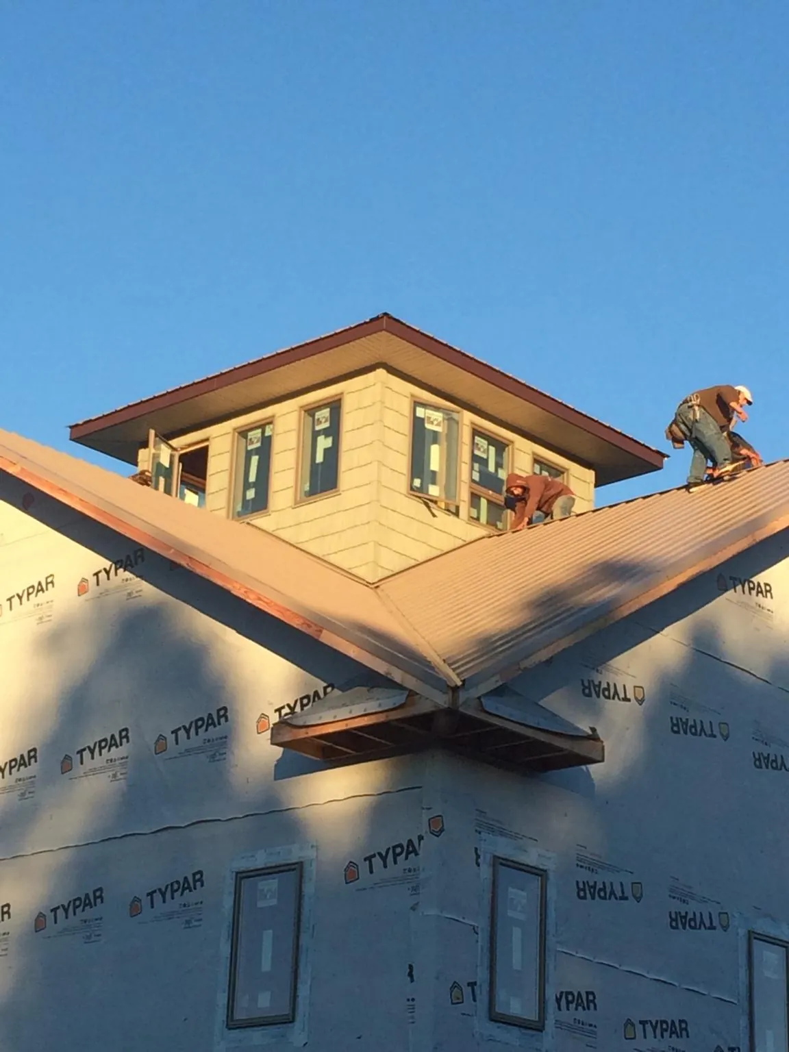 Roofers working around a rooftop cupola on a new metal roof at sunset — Roof Waterproofing in West Wareham by Roofing Brothers